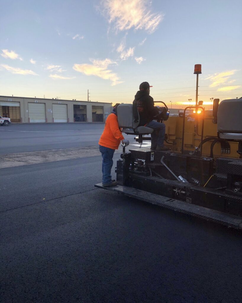 Paving crew running the asphalt paver at sunrise
