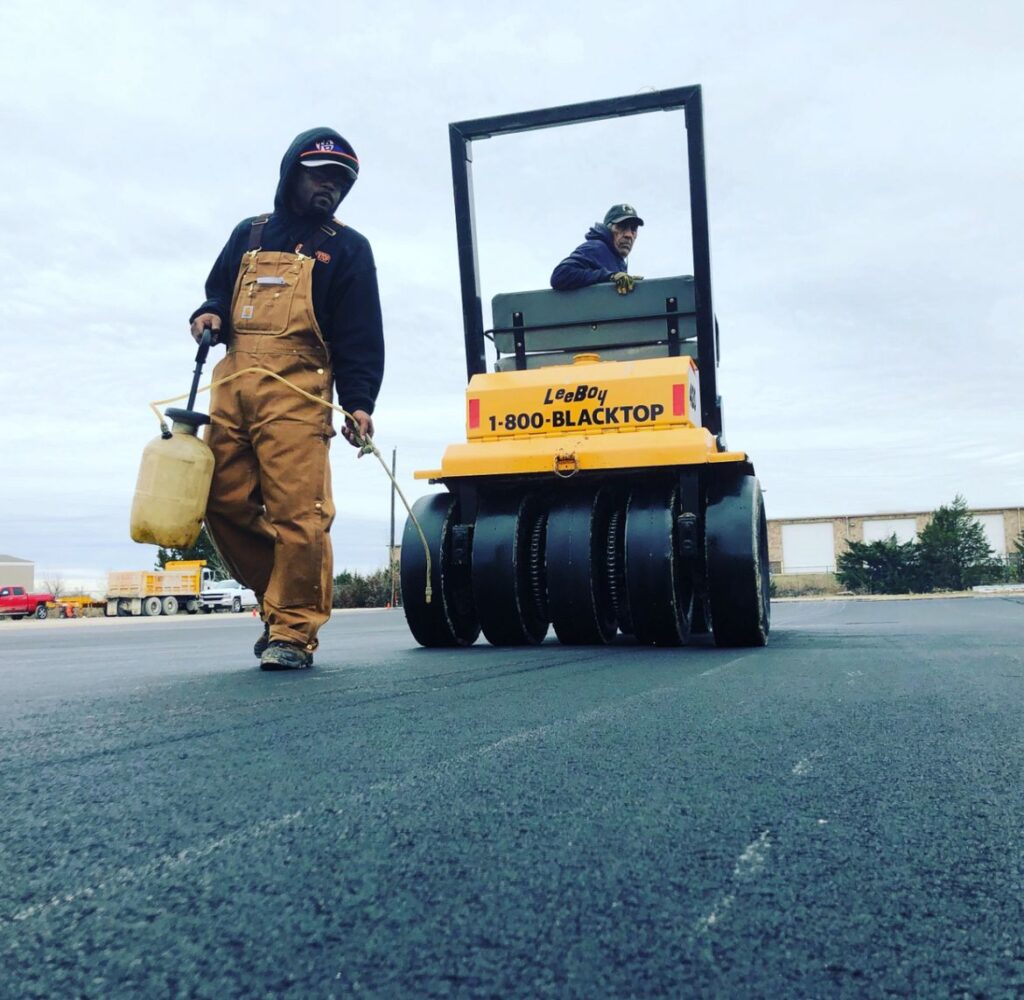 Crew member and roller compacting new asphalt