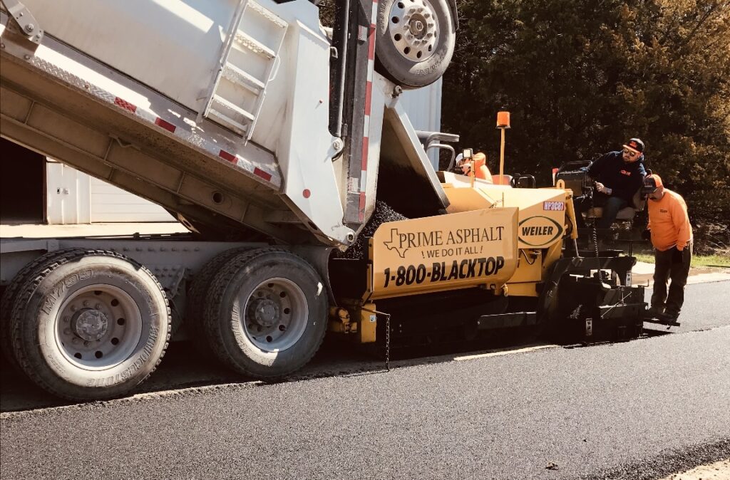 Dump truck feeding hot mix into the paver