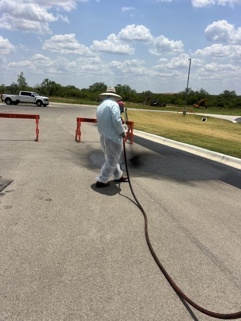 Spraying sealcoat on an asphalt drive